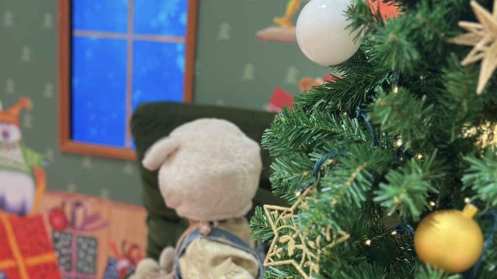 クリスマスツリーの隣に座る赤ちゃん